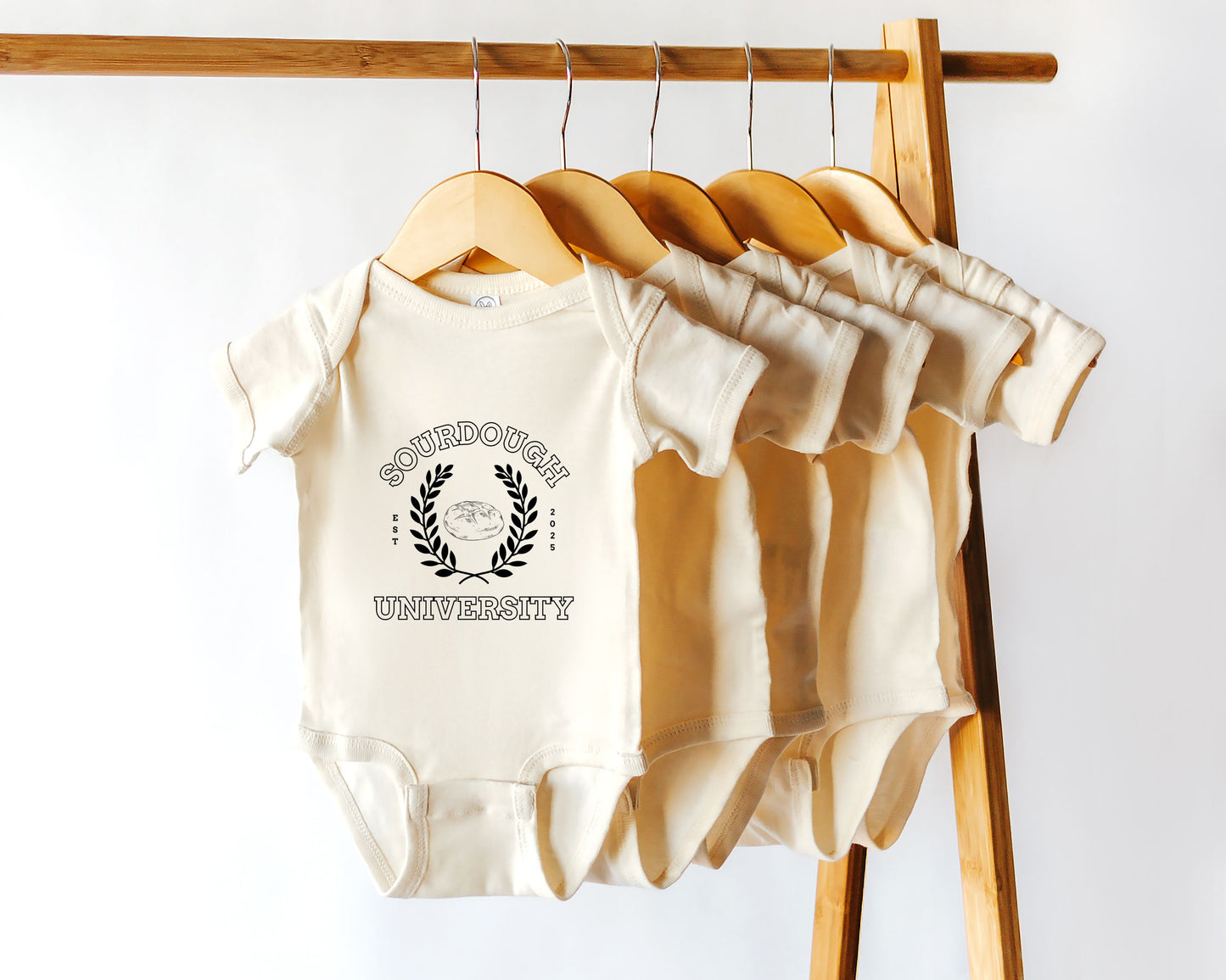A short sleeve baby onesie with 'Sourdough University' printed on the front.
