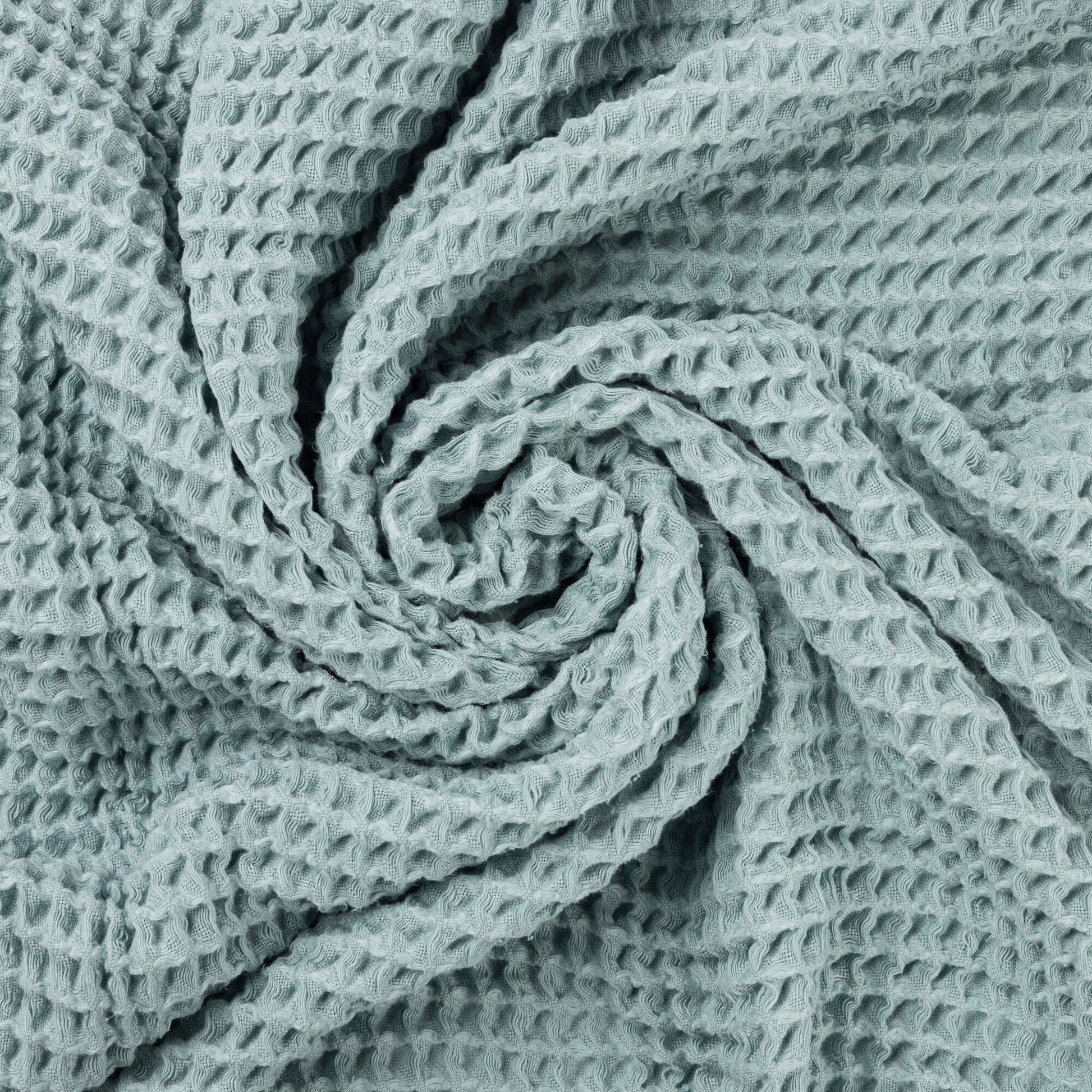 Close up photo of waffle texture of light blue baby blanket.