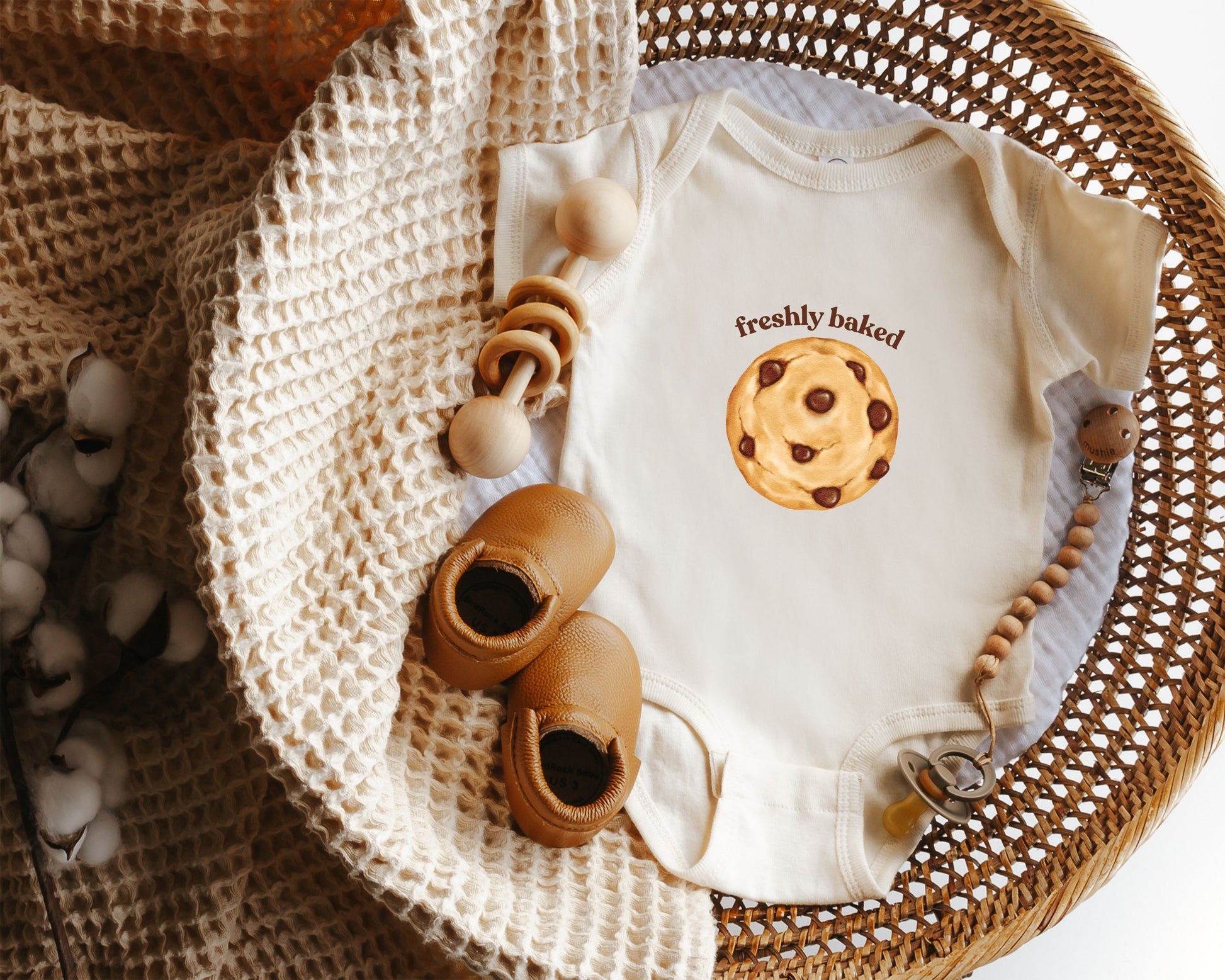 Short sleeve cotton baby onesie with a chocolate chip cookie graphic and the text "freshly baked".