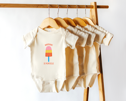 A short sleeve cotton baby onesie with a colorful popsicle graphic and the text "anything is popsicle".