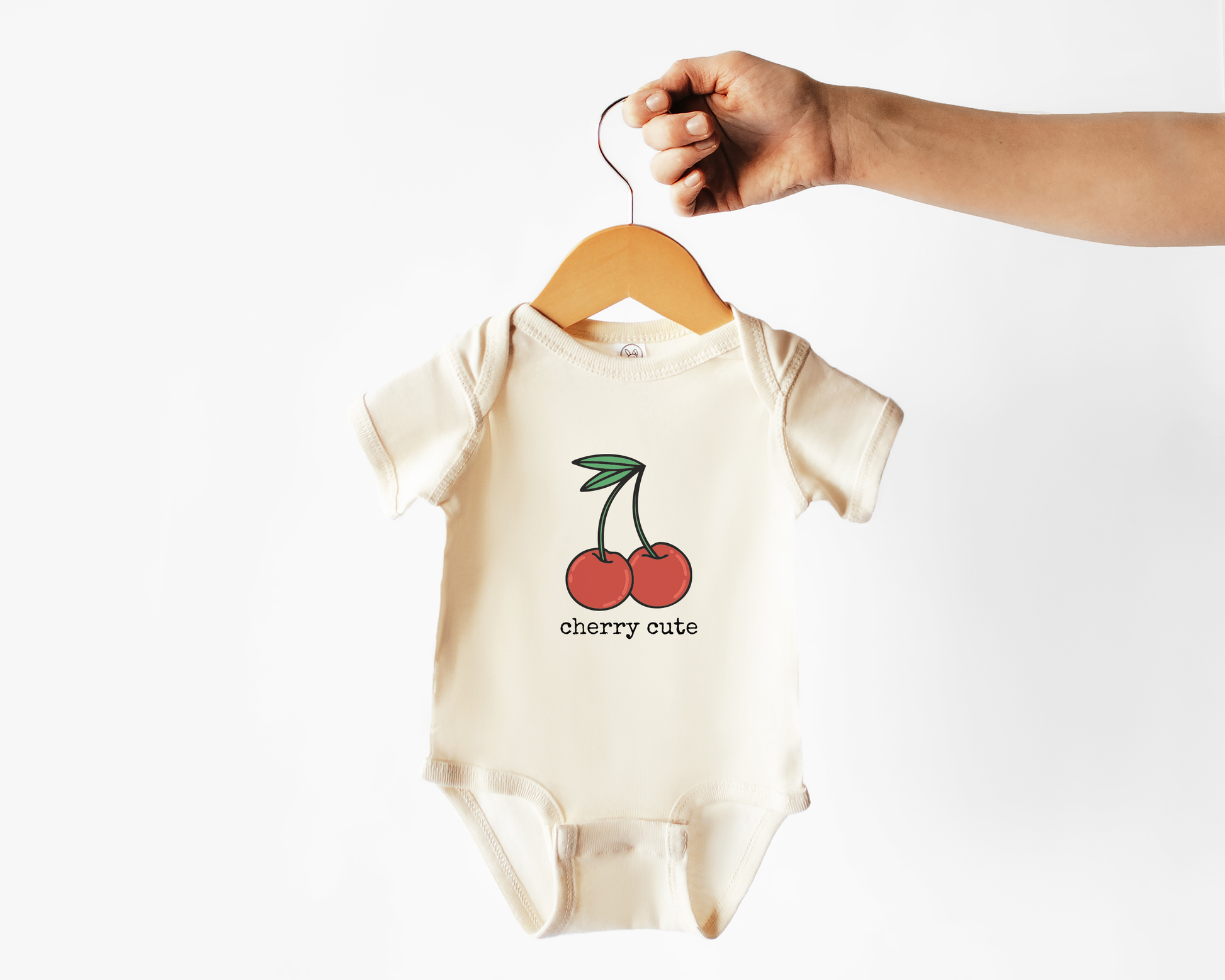 Baby onesie with cherry design and 'cherry cute' text on a hanger against a white background