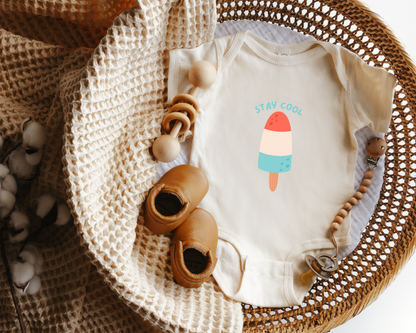 Short sleeve cotton baby onesie with a red, white and blue popsicle graphic and the text "stay cool" styled in a basket.