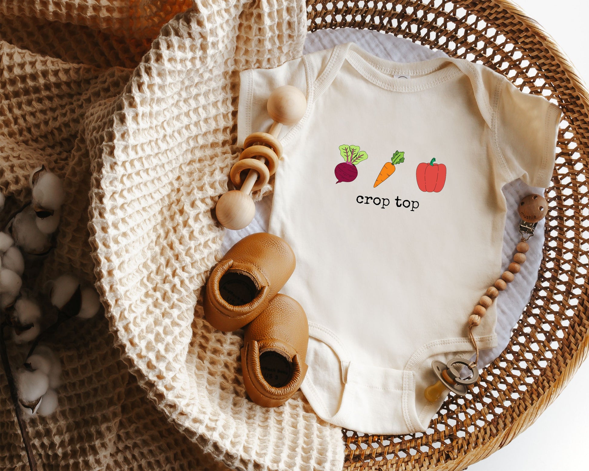 Short sleeve cotton onesie with vegetable graphics of beet, carrot and red pepper with the text crop top in a distressed typewriter style font.