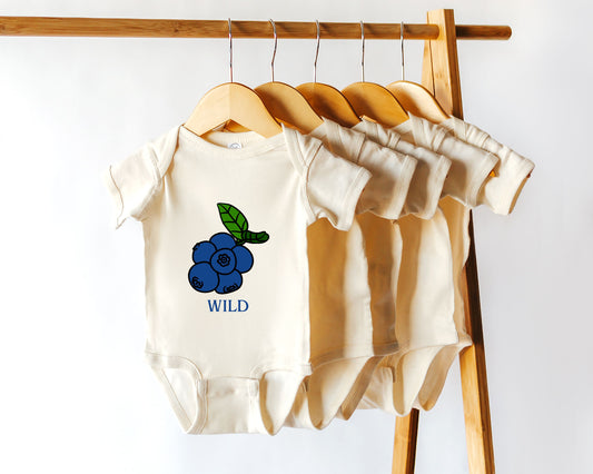 A short sleeve cotton onesie with a blueberry fruit graphic and the text "wild"
