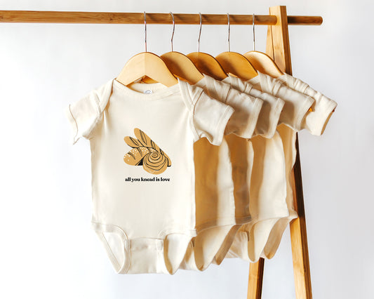 Short sleeve cotton onesie with  homemade baked bread graphics and the phrase all you knead is love