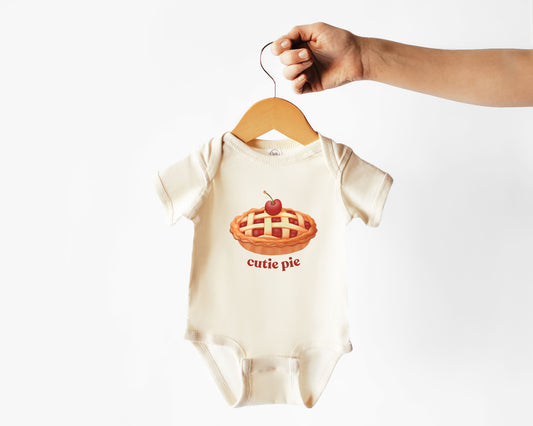 Short sleeve cotton baby onesie with a cherry pie graphic and the text cutie pie. Features an envelope neckline and three snap closure for comfort and easy changing.