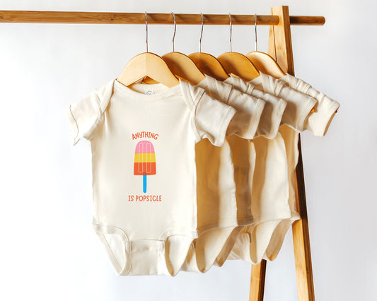 A short sleeve cotton baby onesie with a colorful popsicle graphic and the text "anything is popsicle"
