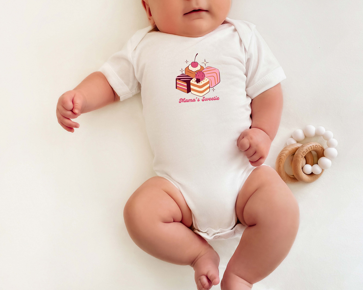 Baby wearing a onesie with cake graphics and 'Mama's Sweetie' on it.