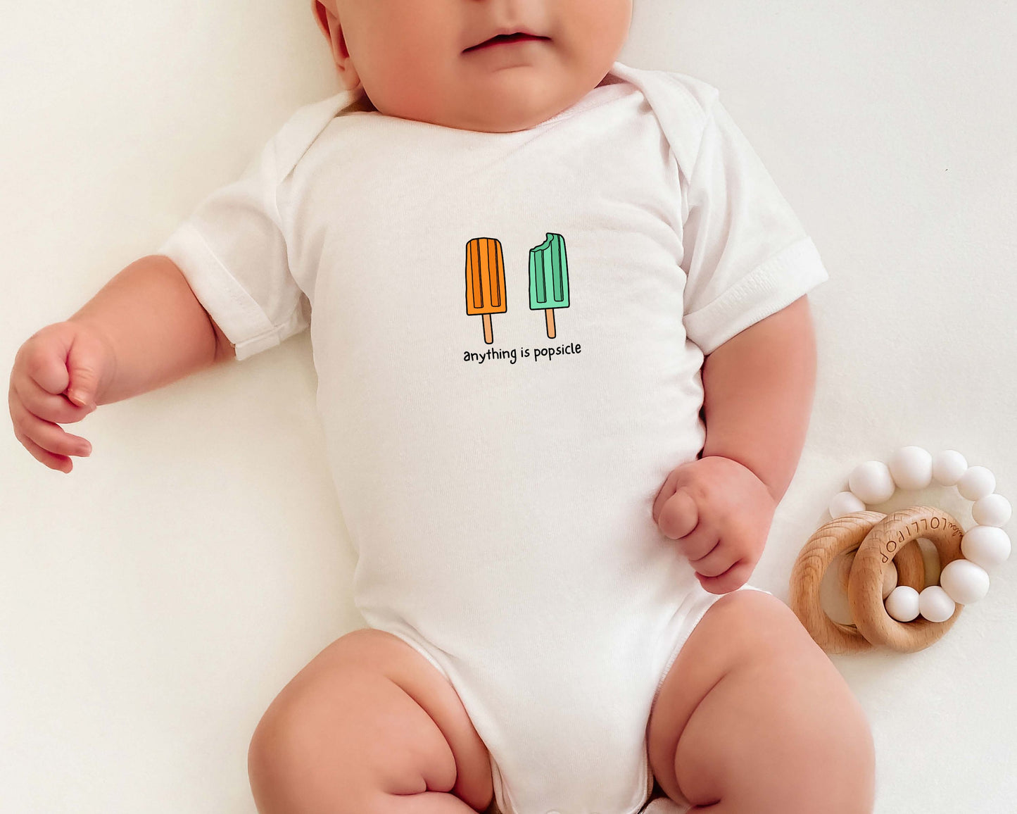 Baby wearing a cotton onesie with summer popsicle graphics and the text "anything is popsicle".