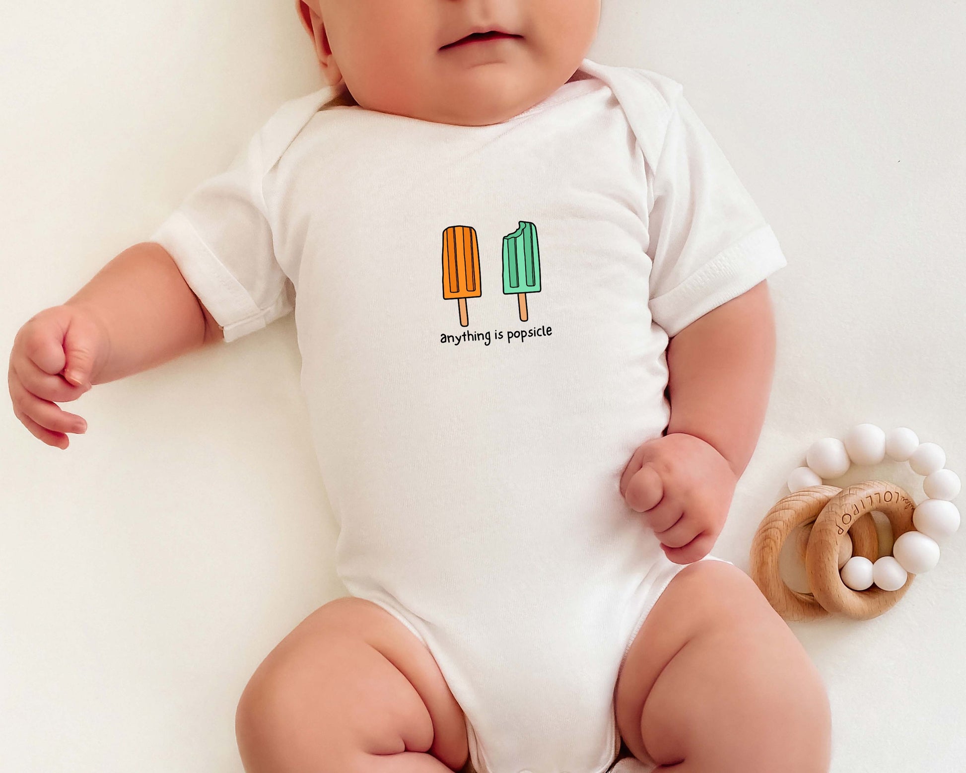 Baby wearing a cotton onesie with summer popsicle graphics and the text "anything is popsicle".