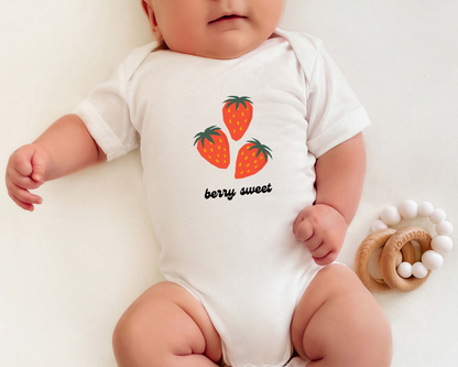 A baby wearing a short sleeve cotton baby onesie with strawberry graphics and the text "berry sweet" on it.