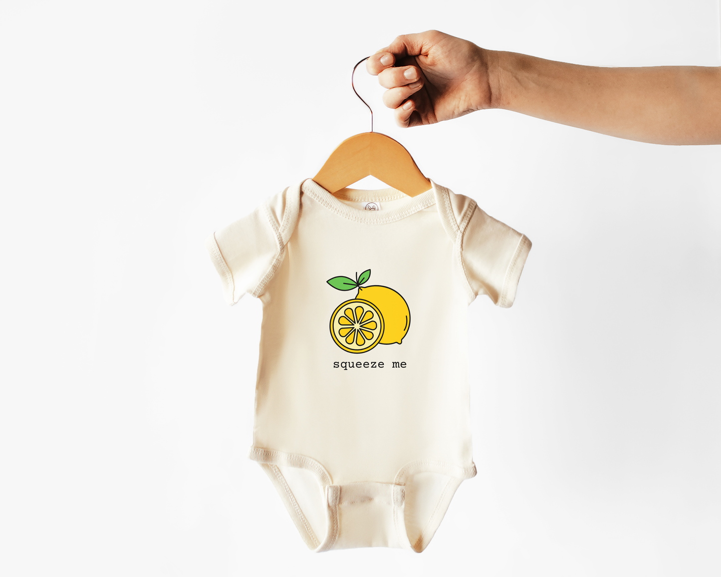 Baby onesie with lemon graphic and 'squeeze me' text on a hanger against a white background