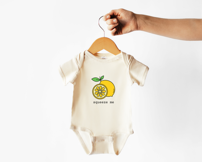 Baby onesie with lemon graphic and 'squeeze me' text on a hanger against a white background